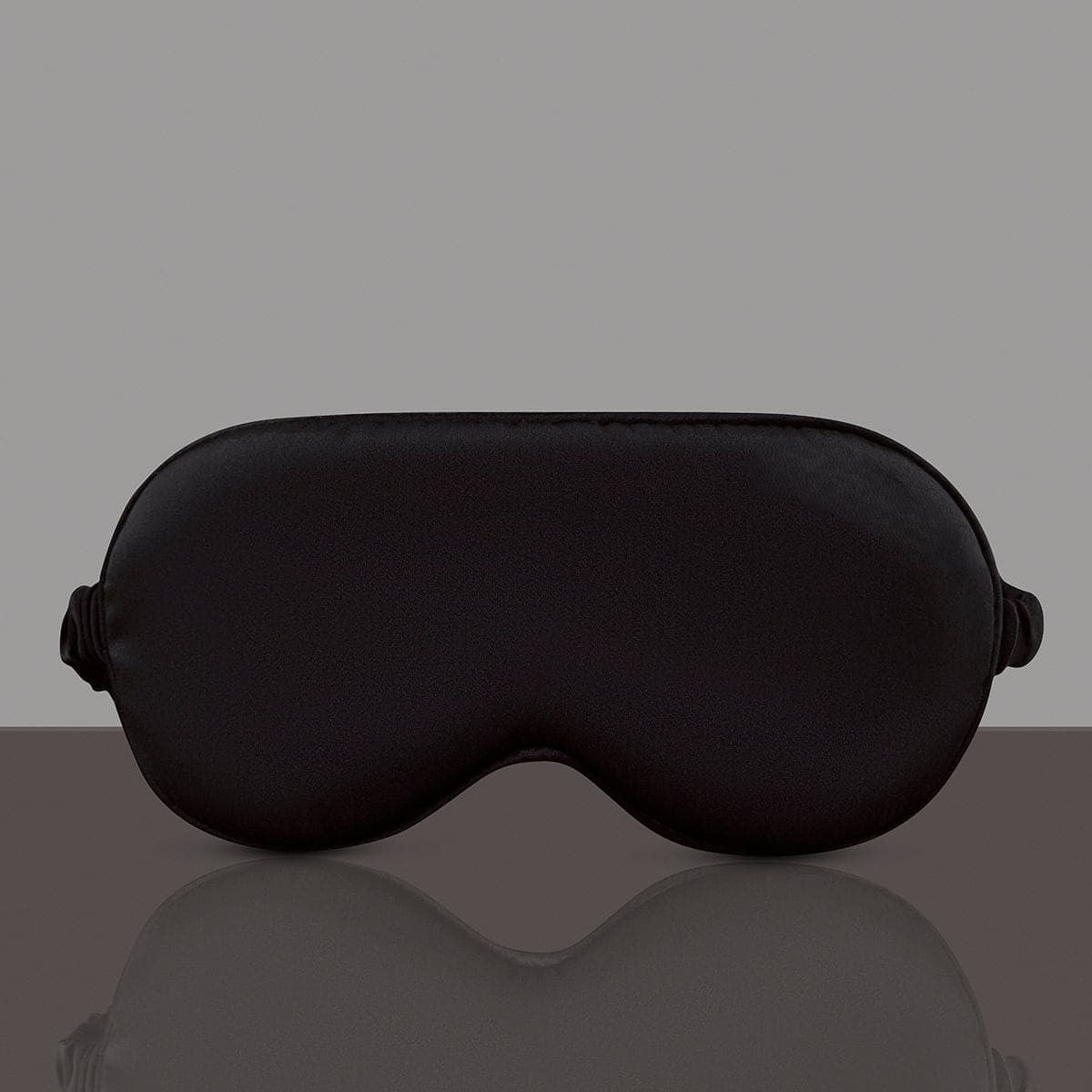 Black sleep mask on a reflective gray surface with a gray background