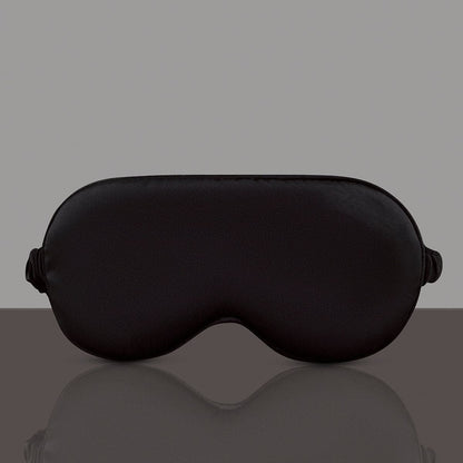 Black sleep mask on a reflective gray surface with a gray background
