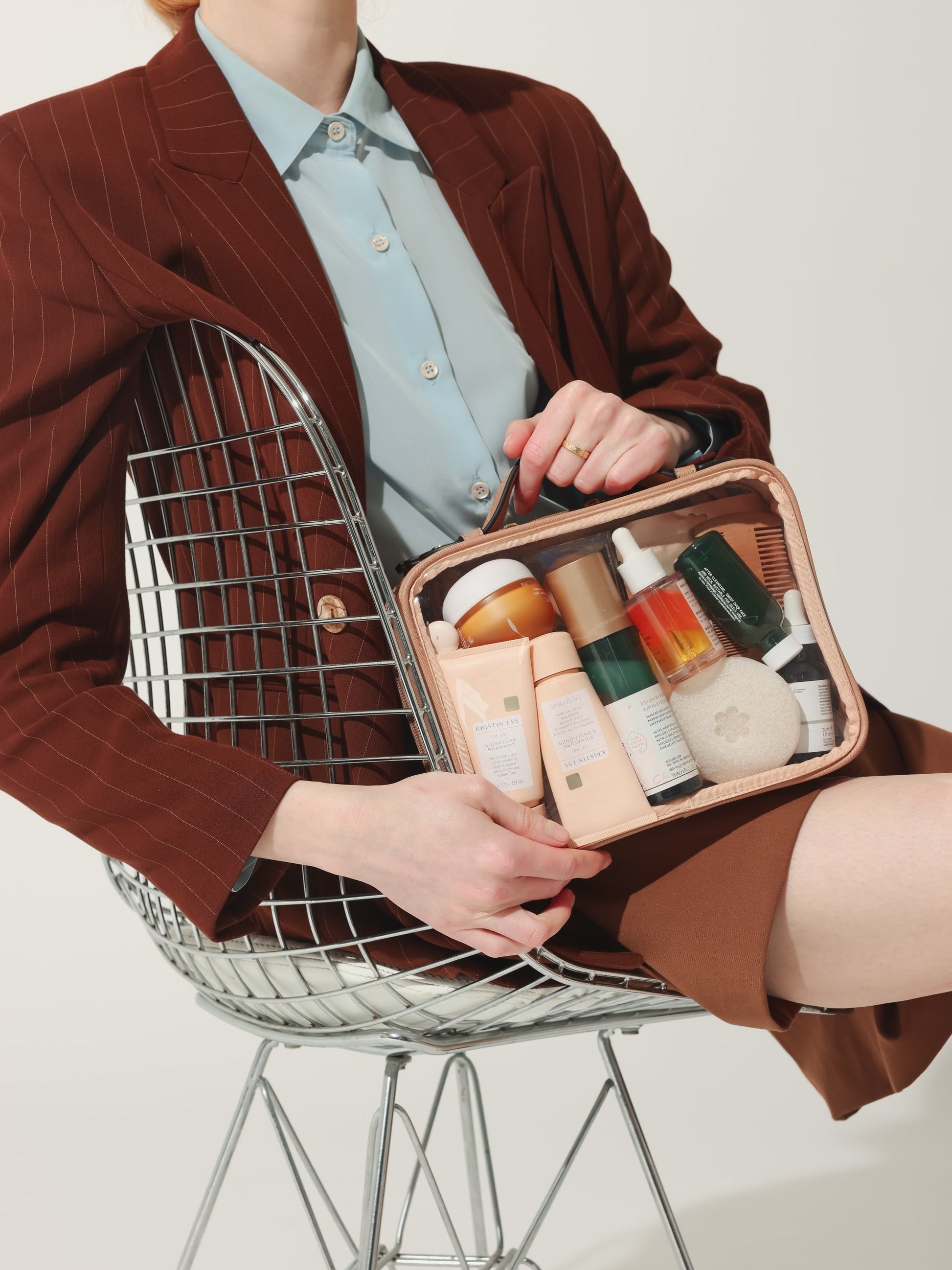 Model holding CALPAK medium transparent makeup case with top handles in beige; CMM2201-CARAMEL