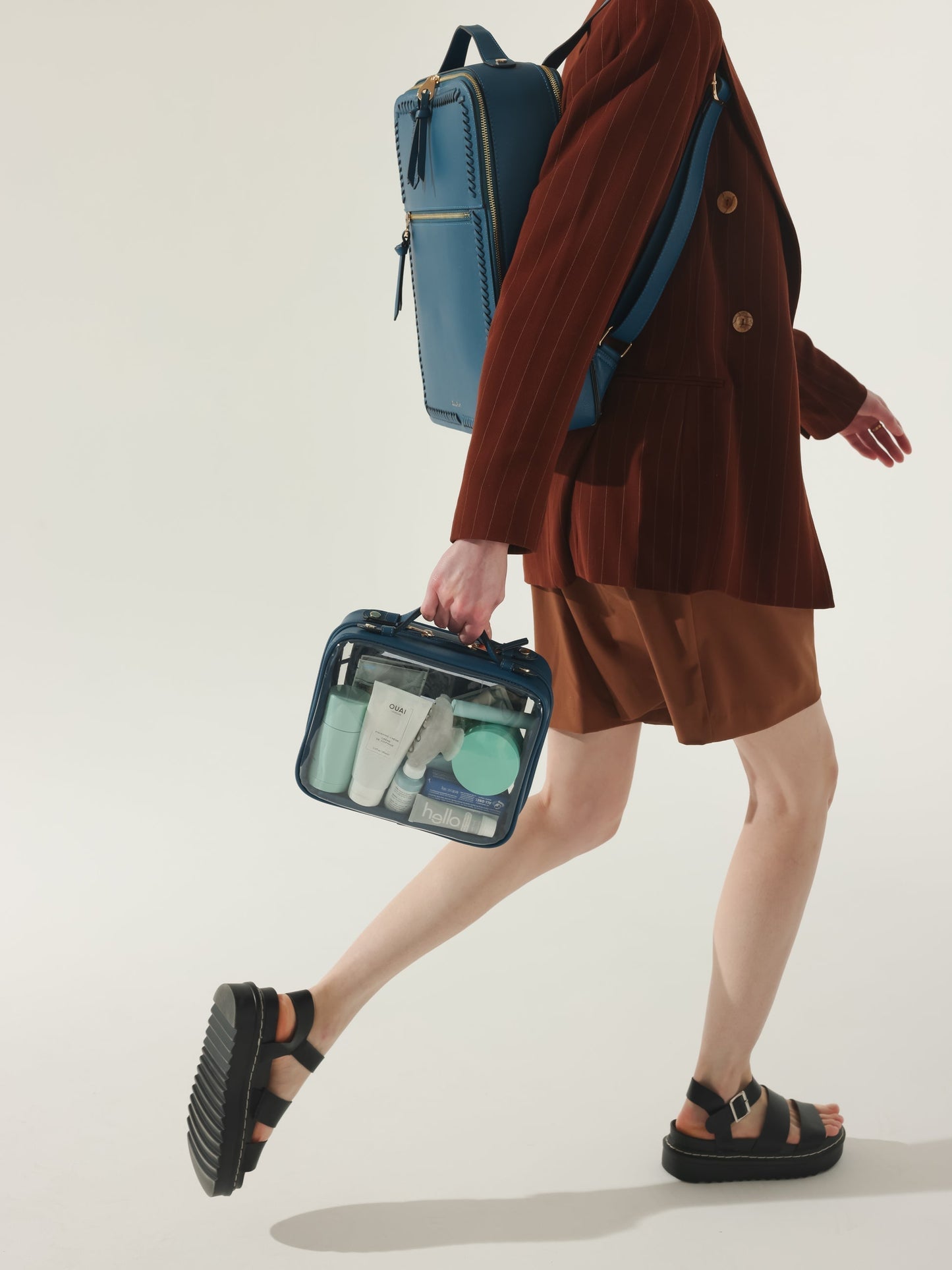 Model holding CALPAK medium clear makeup case with top handles in deep sea blue; CMM2201-DEEP-SEA