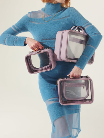 Model holding CALPAK clear makeup case in small, medium and large sizes in lavender purple; CMM2201-LAVENDER